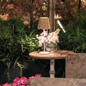 Small table with a lamp and flowers in a garden setting