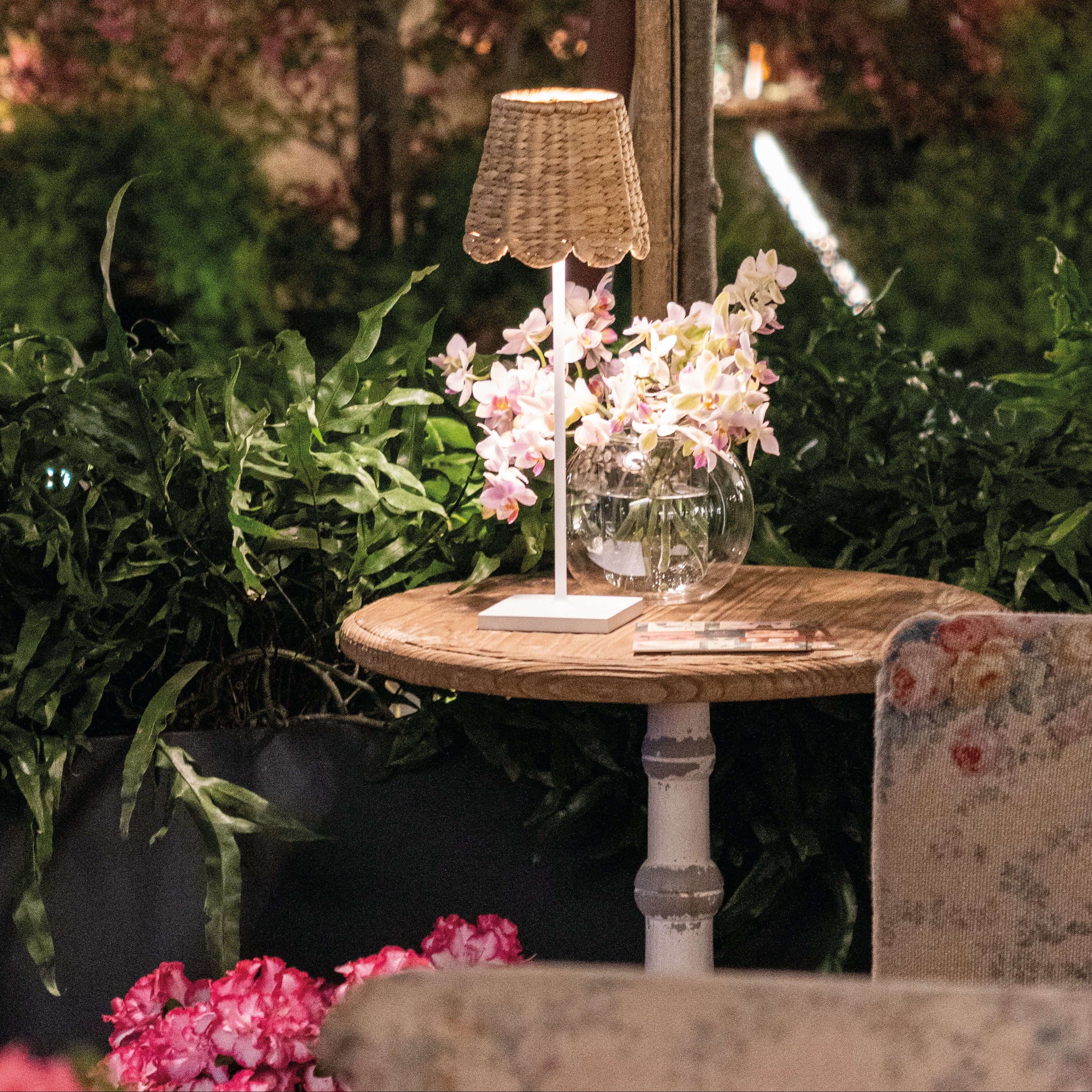 Small table with a lamp and flowers in a garden setting
